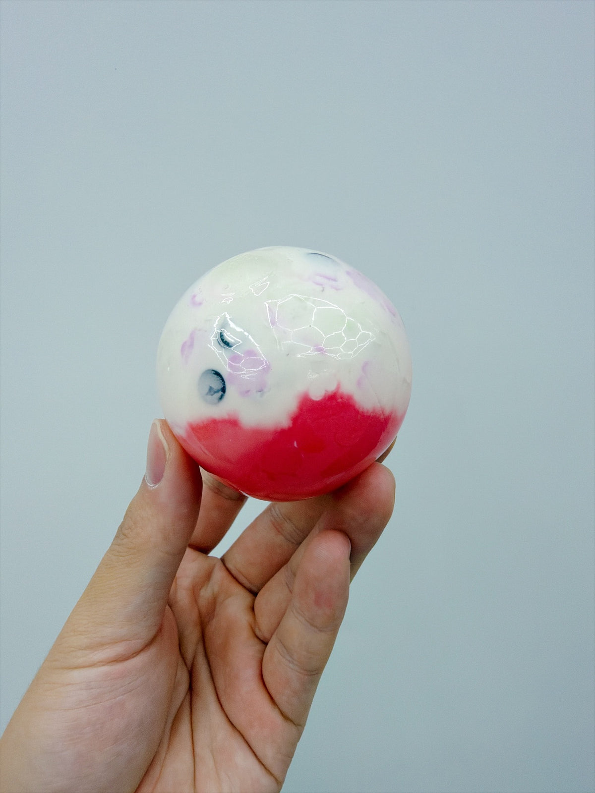 Real Touch Me two-tone crunchy ball squishy in Red in hand