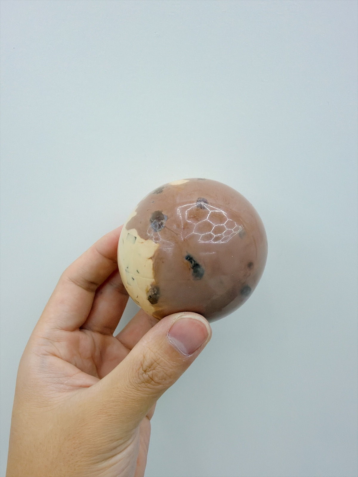 Real Touch Me coffee cocoa ball squishy, glossy marbled side in hand