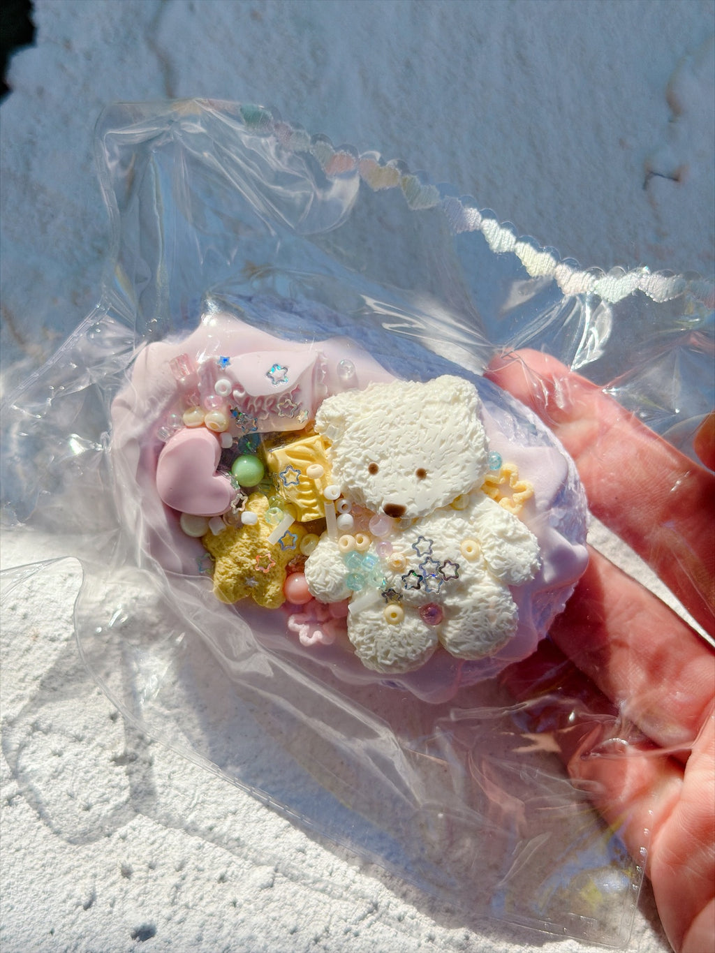Wonder Village bear bun squishy with white teddy bear, pink heart and yellow star charms, in a clear bag